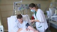 Eine Pflegerin versorgt eine Patientin in einem Krankenhaus. © Screenshot 