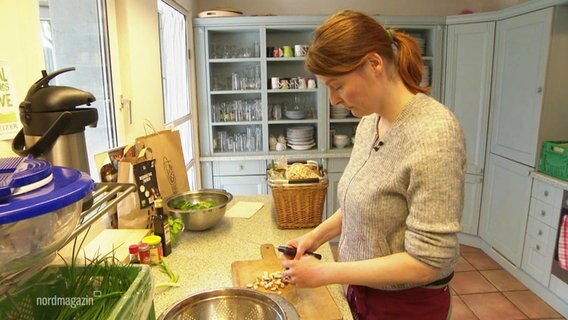 Eine Frau schneidet in einer Küche Gemüse in eine Schüssel. © Screenshot 