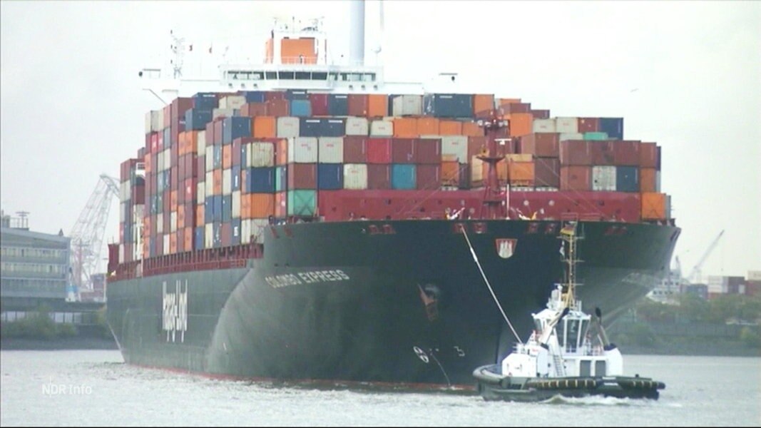 Ein Containerschiff wird von einem Schlepper gezogen.