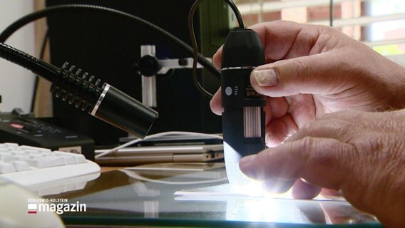 Eine Hand bedient ein leuchtendes Messgerät. © Screenshot 