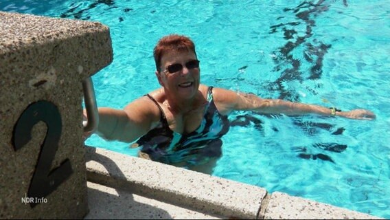 Eine Frau guckt in die Kamera während sie sich im Becken eines Freibads befindet. © Screenshot 