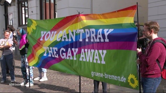 Demonstrierende halten ein Banner mit der Aufschrift: "You can't pray the gay away" © Screenshot 