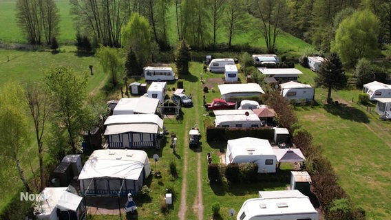 Blick aus der Vogelperspektive auf mehrere Stellplätze eines Campingplatzes und dessen Bewohner. © Screenshot 
