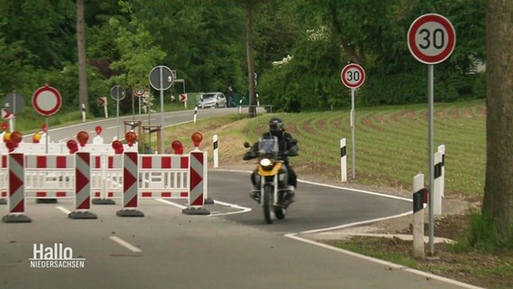 Ein Motorrad fährt durch eine Straßensperre. © Screenshot 