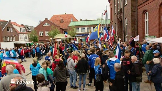 Eine Menschenmenge auf einem Platz mit verschiedenen Landesflaggen. © Screenshot 