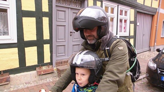 Ein kleiner Junge mit seinem Vater auf einem Moped. © Screenshot 