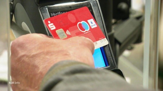Eine Person hält eine EC-Karte vor ein EC-Kartenlesegerät. © Screenshot 