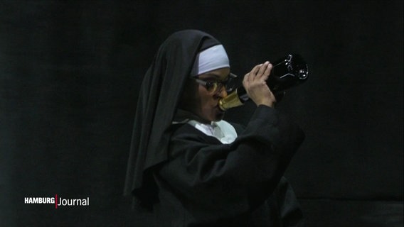 Solistin Levy Sekgapane als Nonne trinkt aus einer Champagnerflasche. © Screenshot 