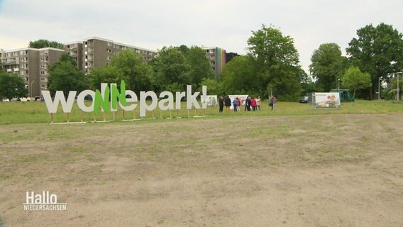 Auf einer Freifläche steht in großen Buchstaben "Wollepark", vor die beiden 'L' wurden zwei grüne große 'N' gesetzt. Hochhäuser im Hintergrund. © Screenshot 