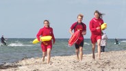 Drei Jugendliche in Kleidung des DLRG am Strand. © Screenshot 