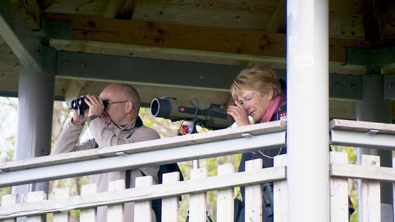 Zwei Menschen mit Ferngläsern auf einem Beobachtungsturm. © Screenshot 