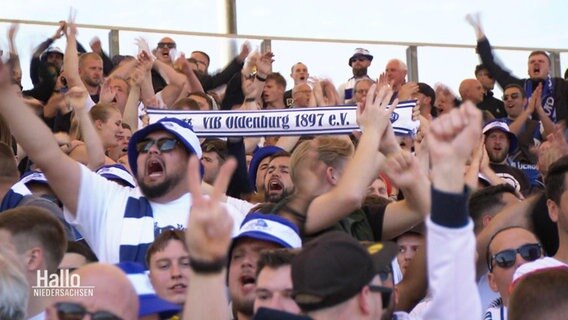Fussballfans halten einen Schal hoch. © Screenshot 