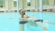 Ein Schwimmtrainer übt mit einem Jungen das Schwimmen. © Screenshot 