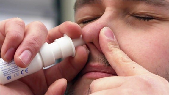 Ein Mann sprüht sich Nasespray in ein Nasenloch. © Screenshot 