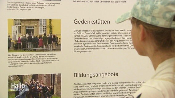 Blick über die Schulter eines Mädchens, dass sich eine Informationstafel über Gedenkstätten anschaut. © Screenshot 