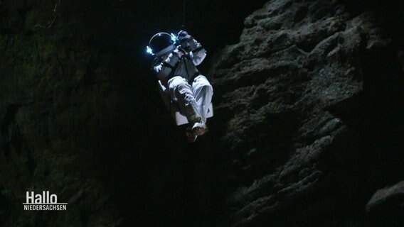 Eine Stuntfrau in einem Raumanzug wird in eine Höhle hinabgelassen. © Screenshot 