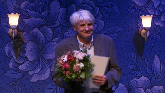 Wolfgang Krischke hält einen Blumenstrauß in der Hand © Screenshot 