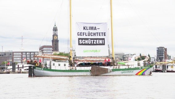 Ein Greenpeace-Schiff mit Transparent "Klimaflüchtlinge schützen" im Hamburger Hafen © Screenshot 