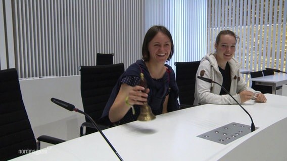 Zwei junge Frauen mit einer Glocke am Tisch der Landtagspräsidentin © Screenshot 