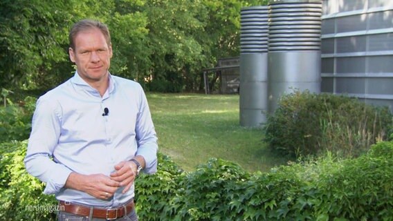 Thilo Tautz moderiert das Nordmagazin - Land und Leute. Er steht auf einer Wiese, im Hintergrund Büsche. © Screenshot 