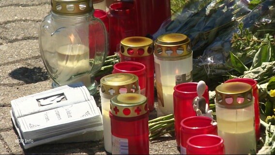 Grabkerzen und Blumen zum Gedenken an ein getötetes Mädchen. © Screenshot 