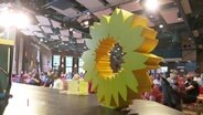 Ein Bildnis einer Sonnenblume steht auf der Bühne beim Mitgliedertreffen der Grünen in Hamburg. © Screenshot 