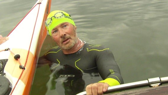 Extremsportler Frank Feldhus neben einem Kajak im Wasser. © Screenshot 
