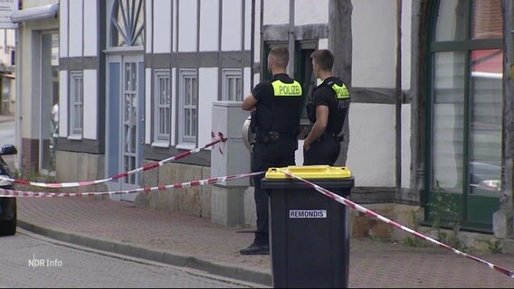 Zwei Polizeibeamte vor einem Fachwerkhaus. © Screenshot 