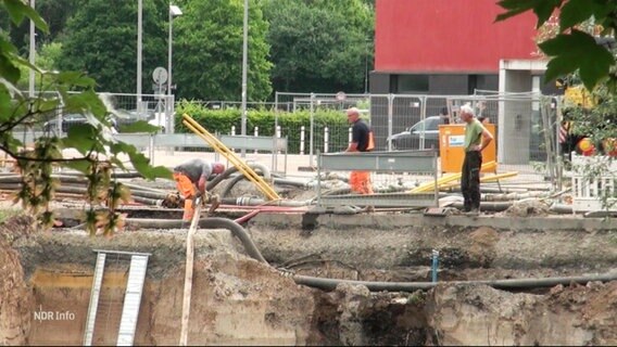 Bauarbeiter arbeiten am Rande einer größeren Grube auf dem Schützenplatz. © Screenshot 