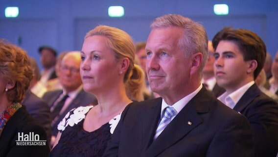 Christian und Betinna Wulff sitzen bei der Ehrung in einem Veranstaltungssaal im Publikum. © Screenshot 