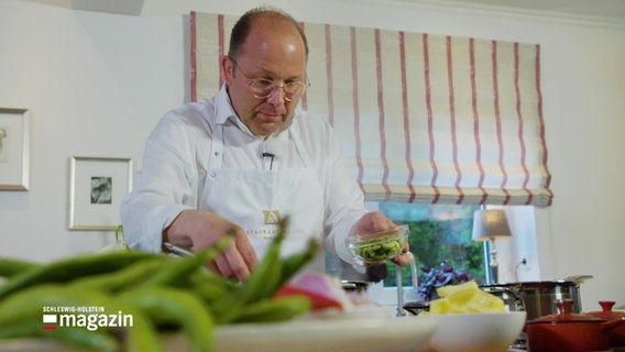 Koch Dirk Luther steht in einer Küche und kocht. © Screenshot 