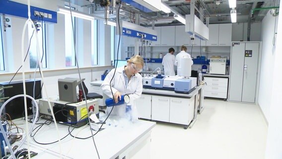 In einem Labor arbeiten mehrere Personen mit weißem Kittel. © Screenshot 
