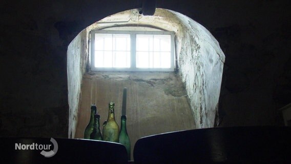 Flaschen vor einem Fenster in einem dunklen Raum © Screenshot 