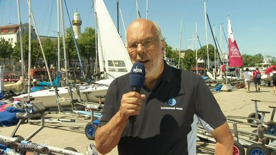 Sportdirektor Peter Ramcke im Interview, im Hintergrund Segelboote. © Screenshot 