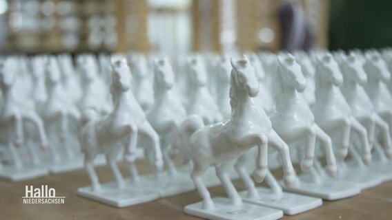 Auf einem Tisch stehen mehrere Hundert Duplikate einer weißen Pferde-Porzellanfigar. © Screenshot 