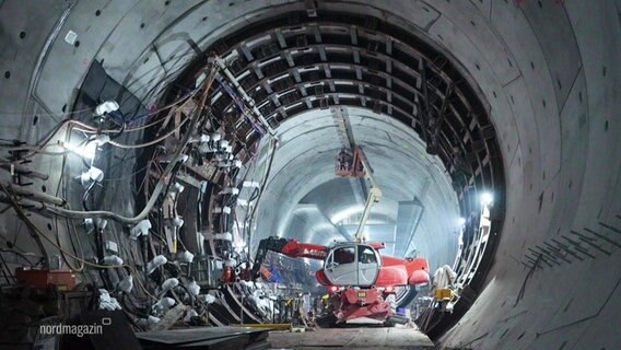 Blick in einen noch unvollendeten Tunnel: In der Mitte ein Fahrzeug mit ausfahrbarem Kran-Arm für Deckenarbeiten. © Screenshot 
