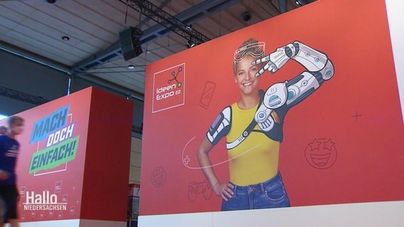 Ausstelungsplakate der Ideen-Expo, die ein lachendes Mädchen mit illustriertem Roboter-Arm, das ein Peace-Symbol in die Kamera hält zeigen. © Screenshot 