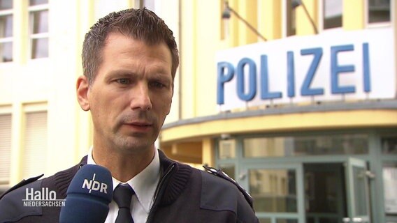 Ein Polizeibeamter spricht in ein Mikrofon © Screenshot 