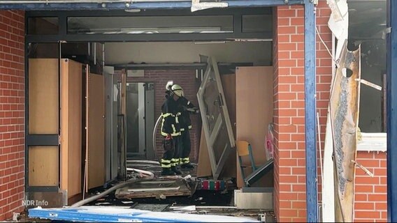 Zwei Feuerwehrmänner stehen in dem Flur der durch eine Explosion zerstörten Schule in Finkenwerder. © Screenshot 