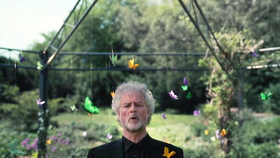 Screenshot: Bassist Andreas Pruys vom NDR Vokalensembles während eines Drehs in Beeten des Botanischen Sondergartens in Hamburg-Wandsbek © Screenshot 