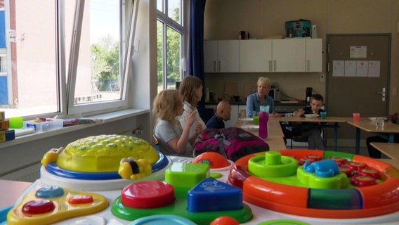 Spielzeug in einer Förderschule, im Hintergrund des Klassenzimmer sitzen Kinder und eine Betreuerin © Screenshot 