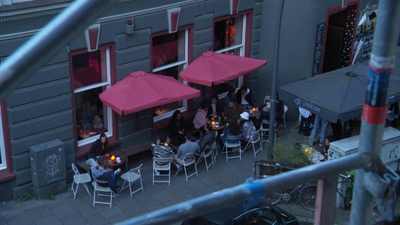 Blick durch Gerüststäbe auf draußen sitzende Gäste einer Bar auf St. Pauli © Screenshot 