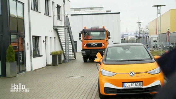 Auf einem Betriebsgelände kommt ein orangefarbener LKW angefahren. © Screenshot 
