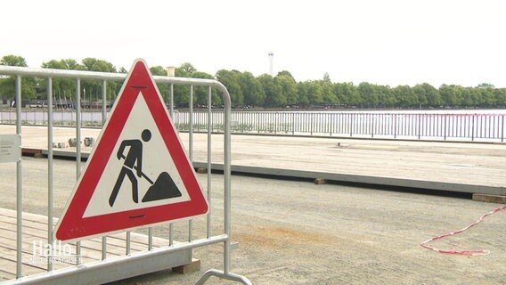 Auf einer Straße steht ein Absperrgitter mit einem Baustellen-Warnschild. © Screenshot 