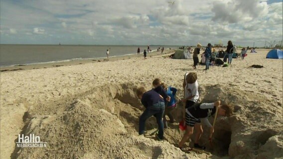 Kinder bauen Sandburgen am Strand. © Screenshot 