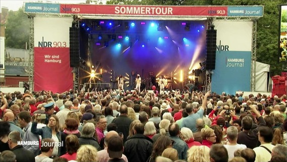 Vor einer Open-Air-Bühne des NDR stehen viele Menschen und lauschen einem Band-Auftritt. © Screenshot 