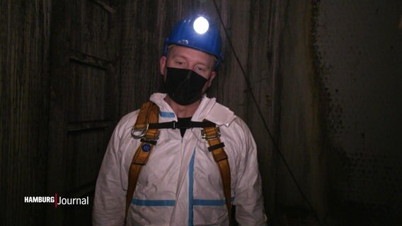 Ein Kanalarbeiter steht mit einer Helmlampe ausgestattet in den unterirdischen Gängen der Hamburger Kanalisation. © Screenshot 