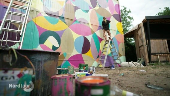 Eine Künstlerin malt eine Wand an. © Screenshot 
