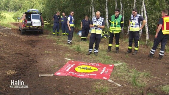 Feuerwehrleute stehen um eine Drohne. © Screenshot 