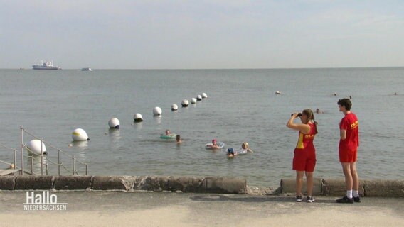 Rettungskräfte des DLRG blicken auf das Meer. © Screenshot 